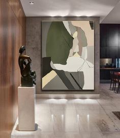 an abstract painting hangs on the wall next to a sculpture in a modern living room