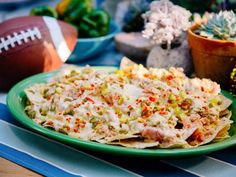 a green plate topped with nachos next to a football