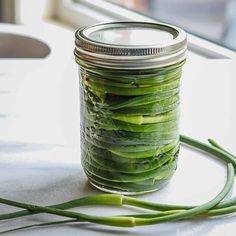 a jar filled with green vegetables sitting on top of a table