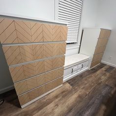 an empty room with wooden flooring and white cabinets