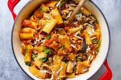 a red pot filled with pasta and vegetables