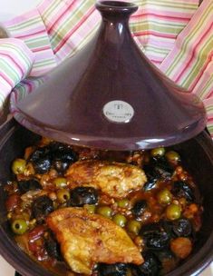 a pot filled with chicken and olives on top of a stove