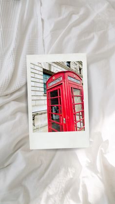 a red phone booth sitting on top of a white sheet