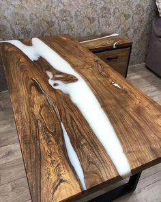 a table made out of wood and white paint on it's surface, with a couch in the background