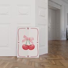 two cherries with pink bows are on the floor in front of a white wall