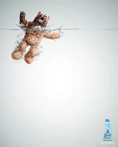 a teddy bear floating in the water next to a bottle