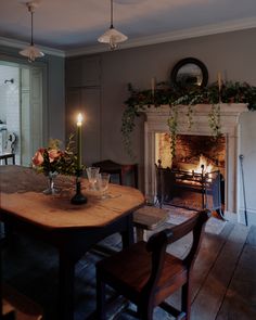 a dining room table with candles and flowers on the top, in front of an open fire place