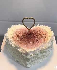 a heart shaped cake with white frosting and sprinkles on the top