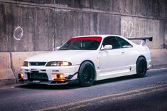 a white car parked in front of a wall