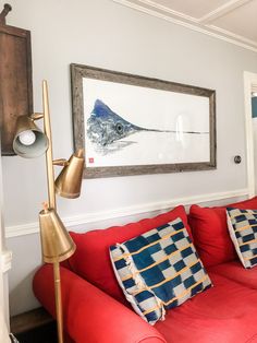 a living room with red couches and a painting hanging on the wall above it