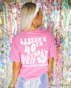 a woman wearing a pink shirt and sequins in front of a colorful wall