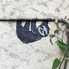 a slotty hanging on the side of a building next to a plant with purple flowers