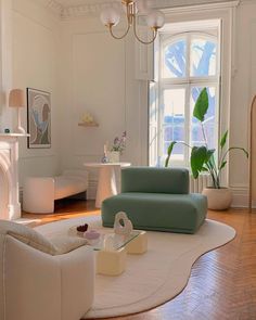 a living room filled with furniture and a fire place under a chandelier in front of a window