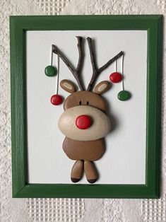 a wooden reindeer with christmas decorations hanging from it's antlers in a green frame