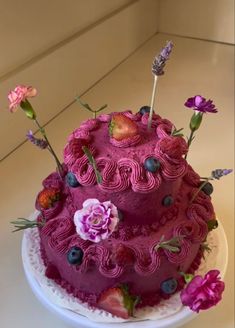 a three tiered cake decorated with flowers and berries