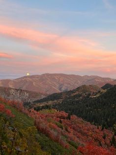 the sun is setting in the mountains with colorful trees