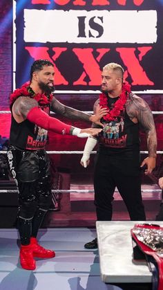 two men standing next to each other in front of a wrestling ring with the words raw is