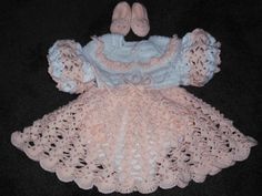 a crocheted baby dress and booties on a black surface