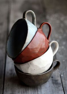 three cups stacked on top of each other in different shapes and sizes, sitting on a wooden surface