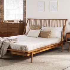 a bed with pillows and blankets on top of it next to a dresser in a bedroom