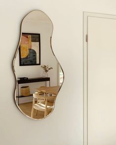 a mirror hanging on the wall next to a dining room table and chair in front of it