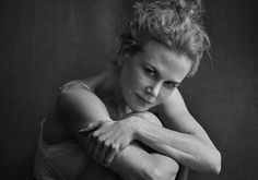 a black and white photo of a woman leaning against a wall with her arms crossed