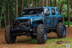 a blue jeep is parked in the woods