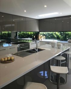 a kitchen with white counter tops and stools next to an island in the middle