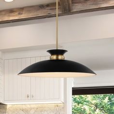 a black and gold pendant light hanging from a ceiling in a kitchen with white cabinets