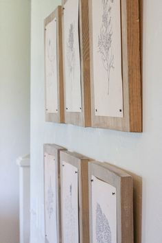 four framed art pieces hanging on the wall in a room with white walls and wood trimming