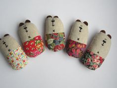 four small stuffed animals are lined up in different colors and patterns, each with a unique pattern on them