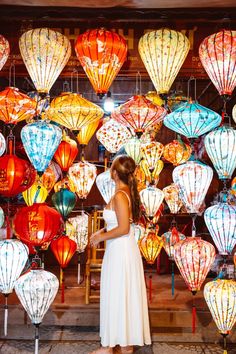 a woman standing in front of many colorful lanterns