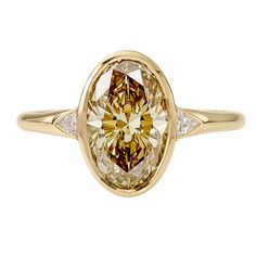 a fancy yellow diamond ring with two diamonds on the band and an oval shaped center stone