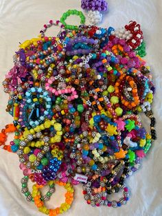 a pile of colorful beaded bracelets laying on top of a white cloth covered table