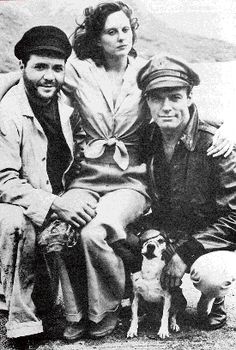 an old black and white photo of three people sitting next to each other with a dog
