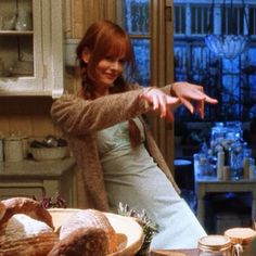 a woman in a kitchen pointing at something