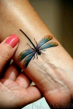 a woman's wrist tattoo with a dragonfly on the left side of her hand
