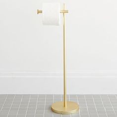 a gold toilet paper holder with a roll of toilet paper on it's side