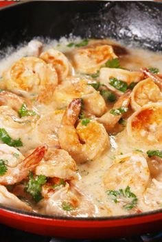 a skillet filled with shrimp and broccoli covered in white sauce on top of a stove