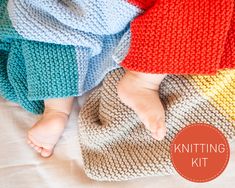 a baby laying on top of a knitted blanket next to another child's feet