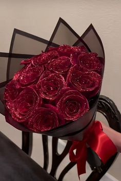 a bouquet of red roses sitting on top of a table next to a black chair