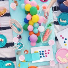 a table topped with plates and cups filled with desserts on top of a blanket