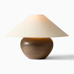 a table lamp with a white shade on it's base and a brown vase underneath