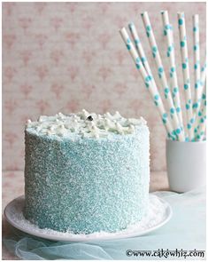 there is a blue cake with white frosting and straws on the table next to it