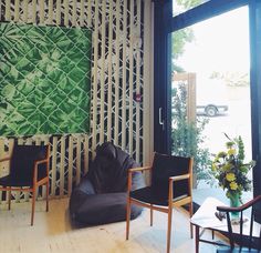 a living room filled with furniture next to a large wall covered in bamboo strips and plants
