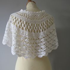 a white crocheted shawl on a mannequin