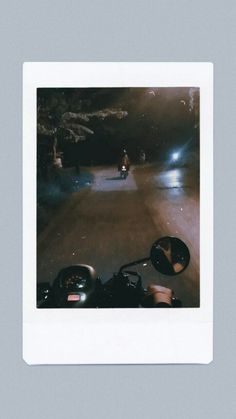 two people riding motorcycles down a street at night