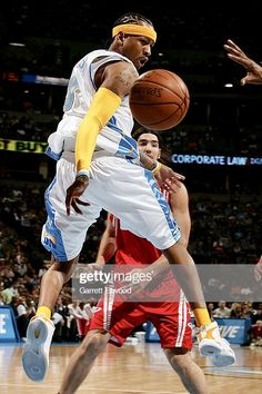 a basketball player jumping up to dunk the ball in front of an opponent during a game