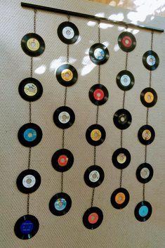 a wall hanging made out of old records with chains attached to it and various colored discs on the chain