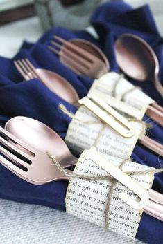 forks and spoons wrapped in twine on top of blue cloth with words written on them